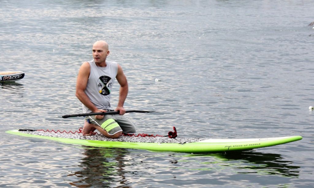 Dean Randazzo kneels on his paddleboard at the 11th annual Paddle For A Cause | Photo Courtesy: Dean Randazzo Cancer Foundation